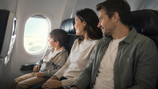Billedet viset en familie på 3, hvor barnet sidder trygt ved sine forældre og kigger ud af vinduet i flyet.